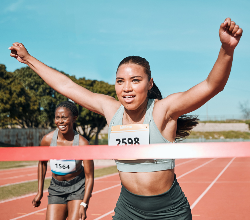 young female athlete running through the finish line rising her hands in the air